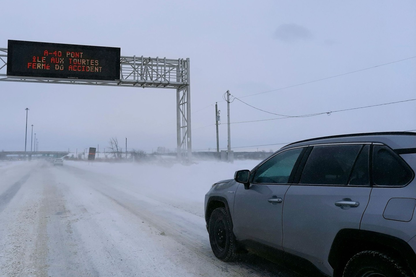 Kältwelle in Kanada: Ein Auto fährt auf der schneebedeckten Ile aux Tourtes-Brücke, die von Ontario nach Montreal führt, während eine Anzeige eine Vollsperrung aufgrund eines wetterbedi...