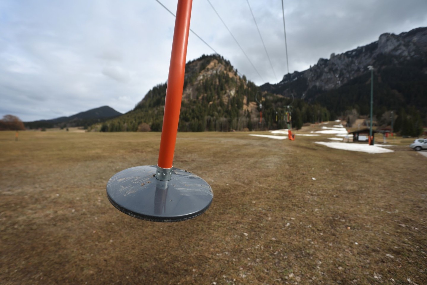 Hier läuft nichts: Teller eines Schleppliftes baumeln an einer Skipiste im bayerischen Schwangau, auf der noch Reste von Kunstschnee zu sehen sind.