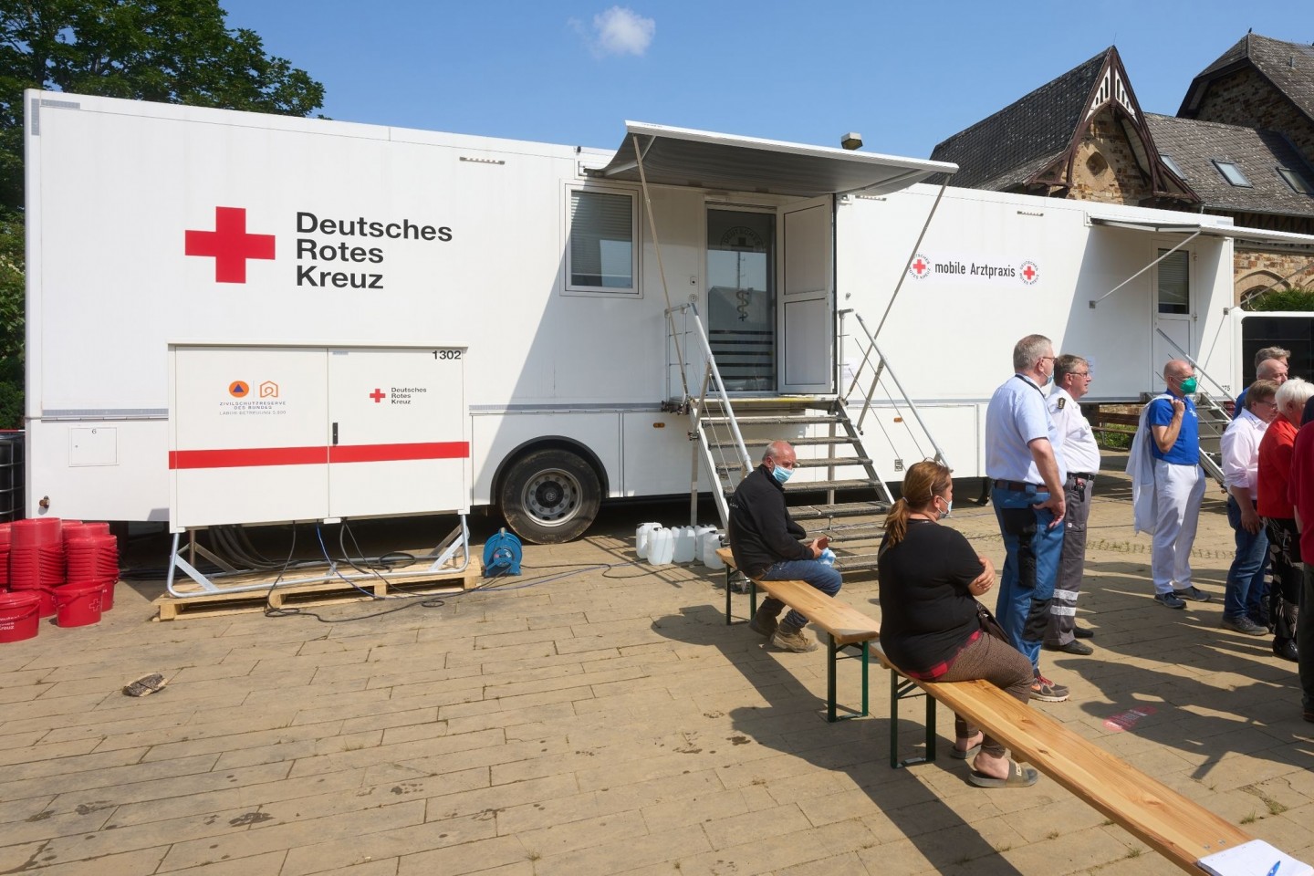Menschen warten vor einer mobilen Arztpraxis des Deutschen Roten Kreuzes in Bad Neuenahr-Ahrweiler.