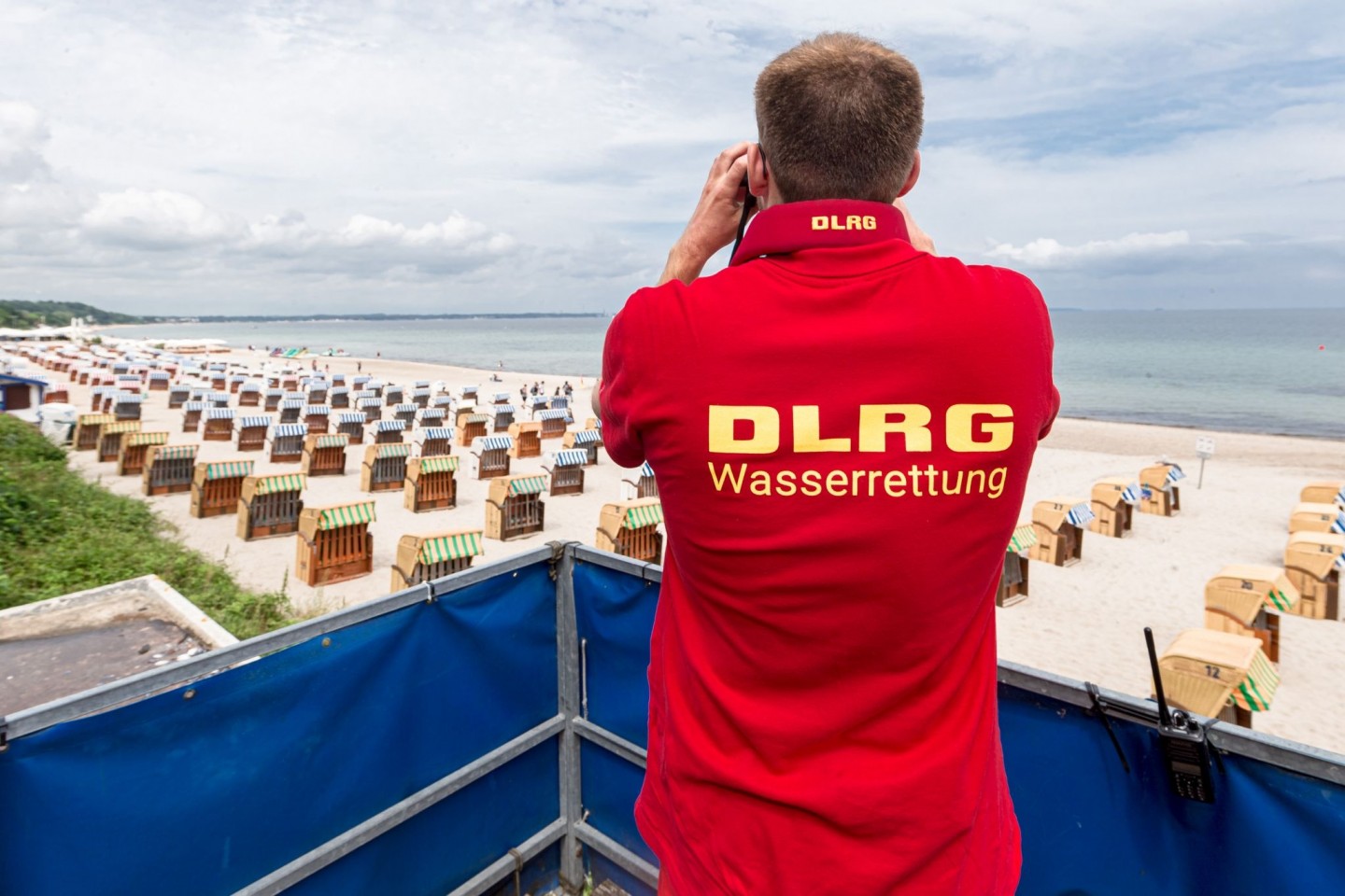 Ein Rettungsschwimmer der Deutsche Lebens-Rettungs-Gesellschaft (DLRG) betrachtet einen Strand. Symbolbild