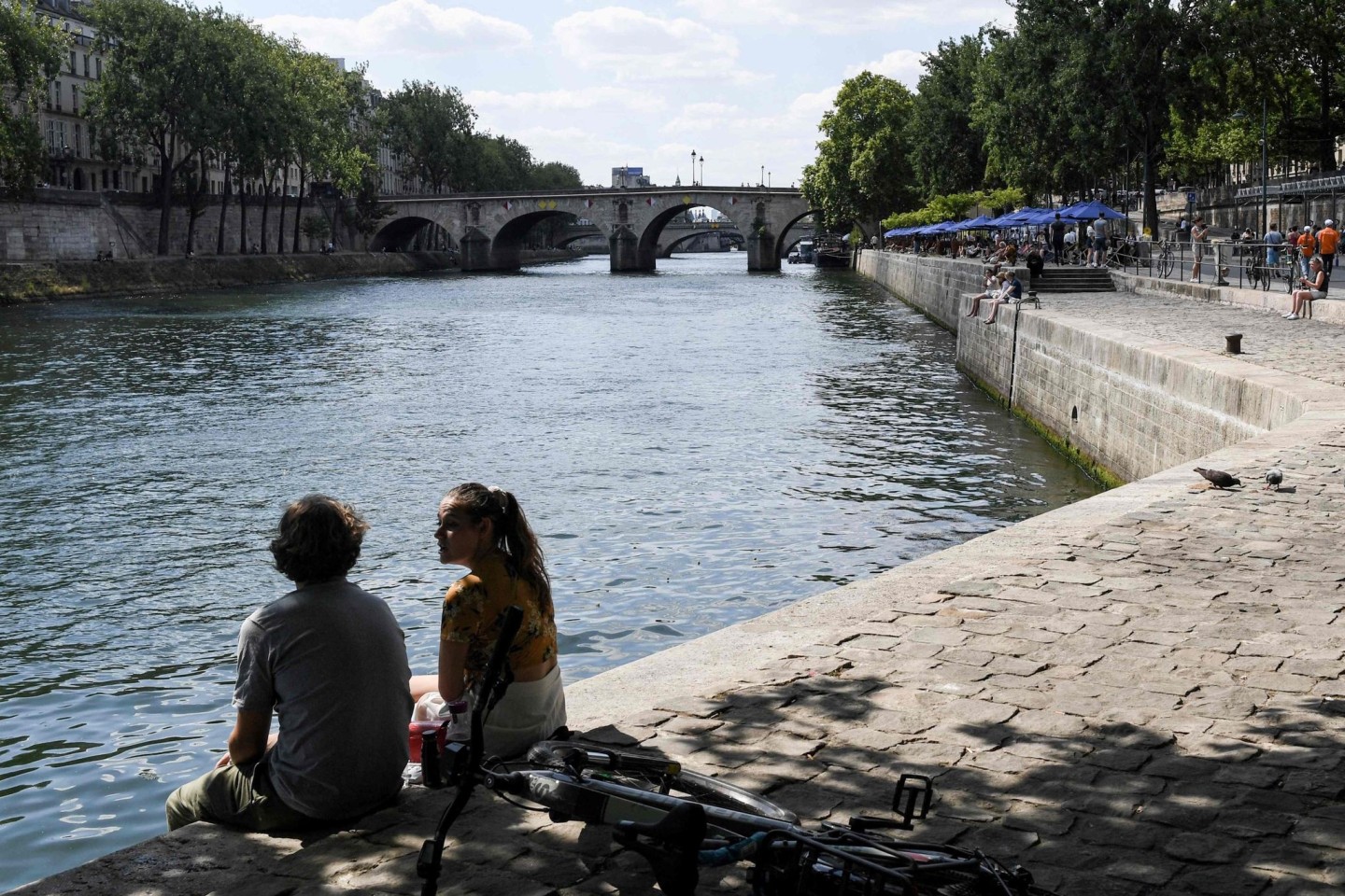Zwei junge Leute sitzen am Ufer der Seine in Paris.