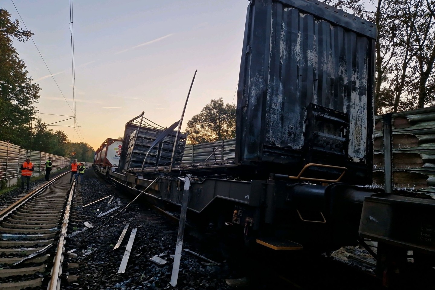 Beschädigte Waggons eines Güterzugs stehen nach einem Brand auf den Gleisen. Das Feuer hatte für Ausfälle und Verspätungen bei der Bahn gesorgt.