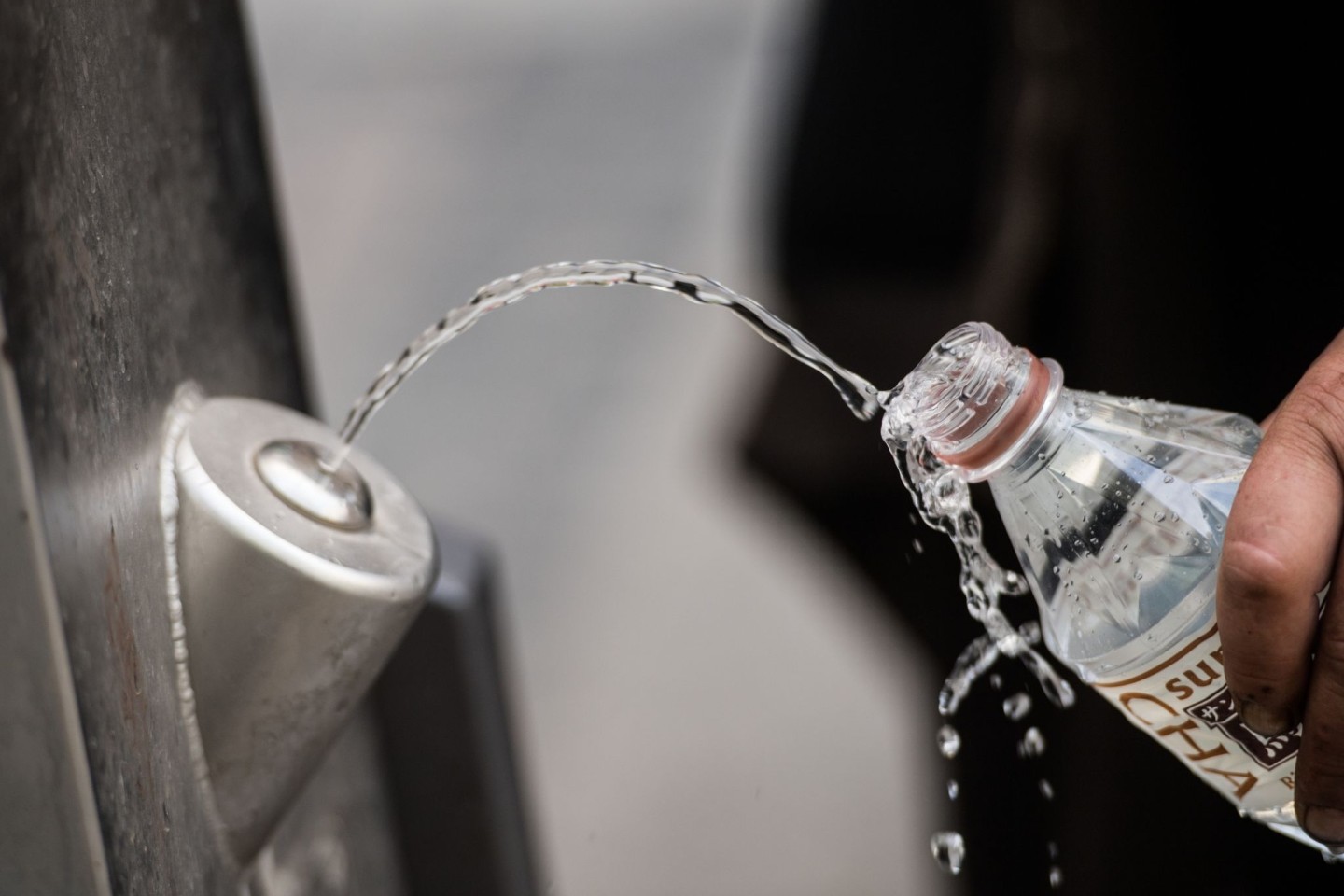 Ein Mann füllt sich an einem Brunnen kostenlos Trinkwasser in die eigene Flasche.