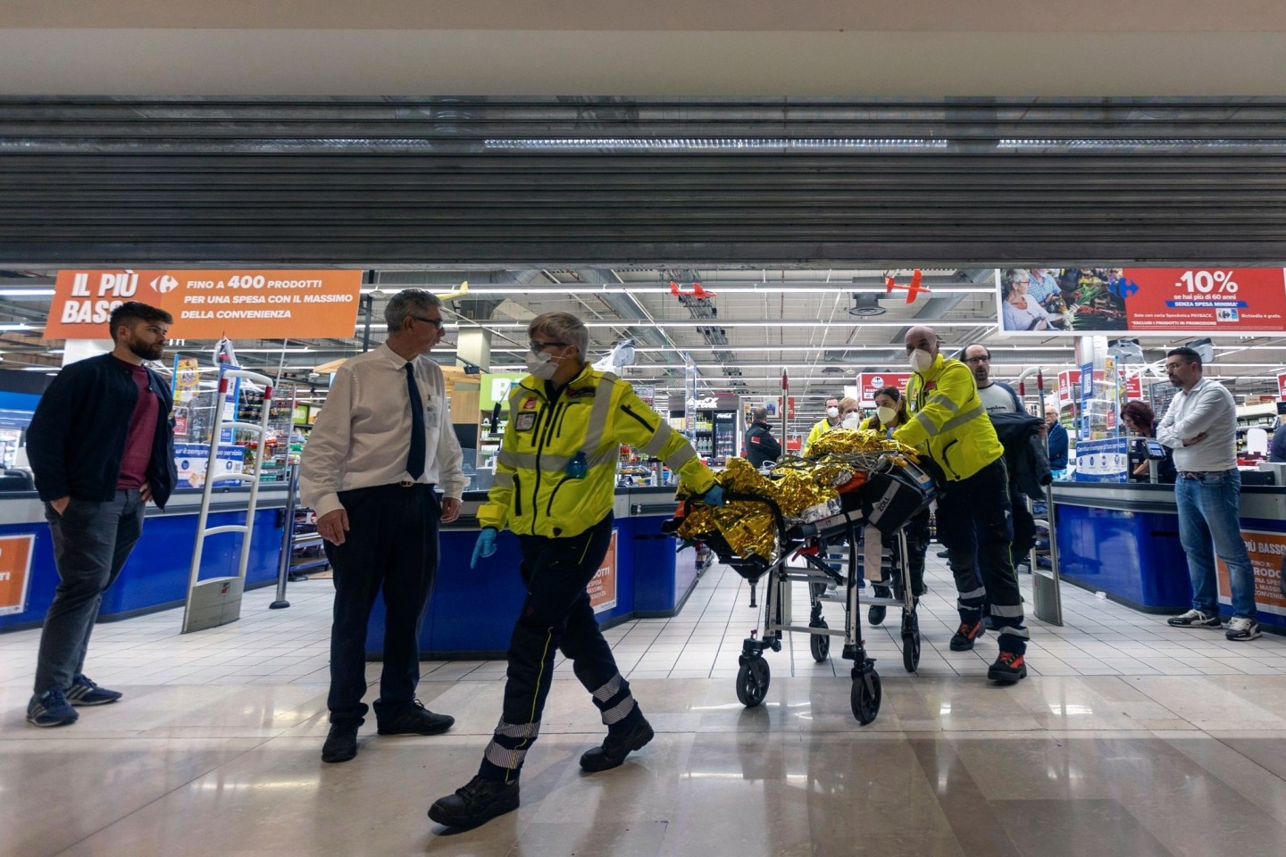 Rettungskräfte transportieren eine verletzte Person aus dem Supermarkt.