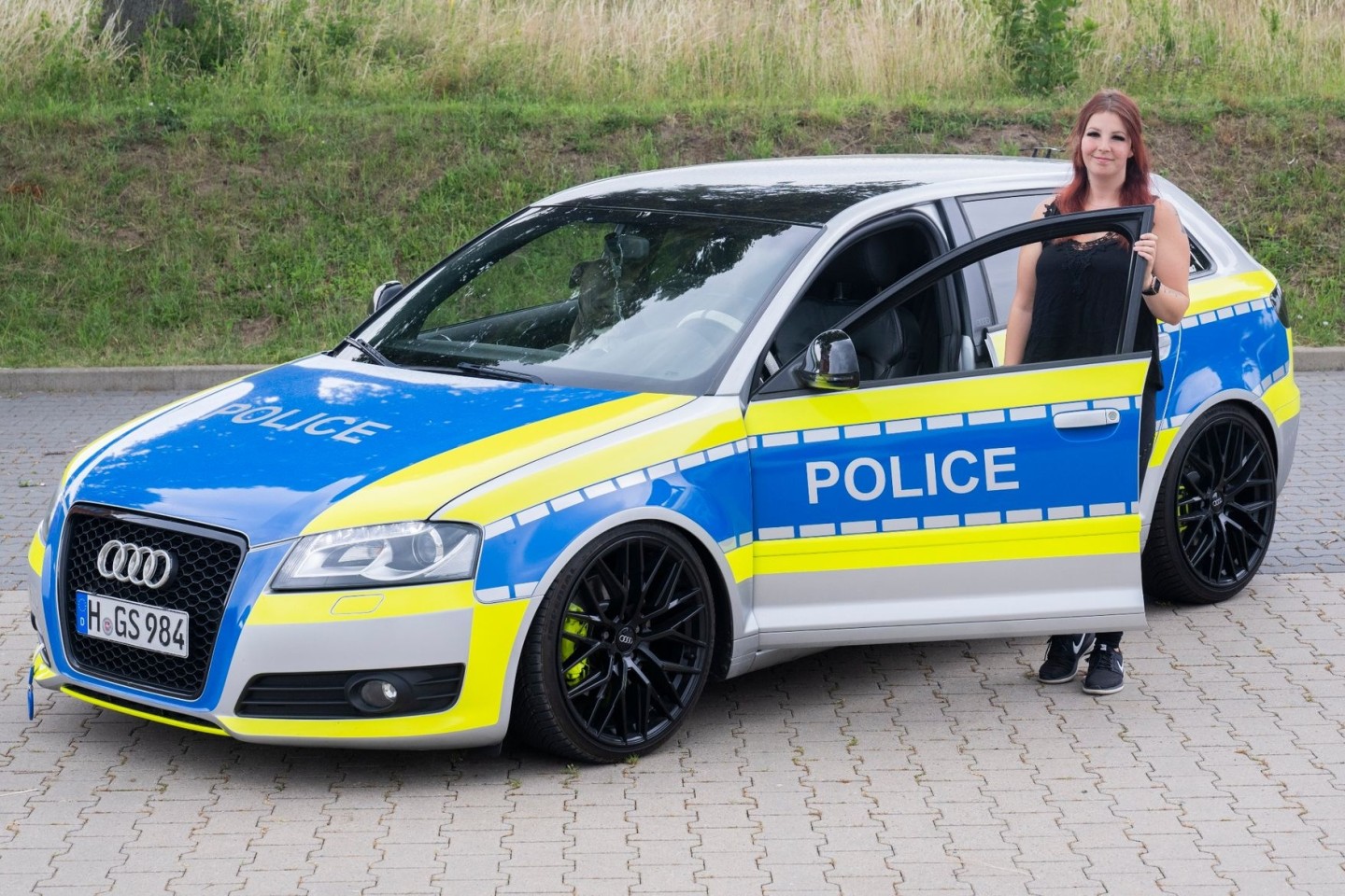 Die Autotunerin Svenja Geertz steht neben ihrem Audi, der ähnlich wie ein Polizeifahrzeug foliert ist.