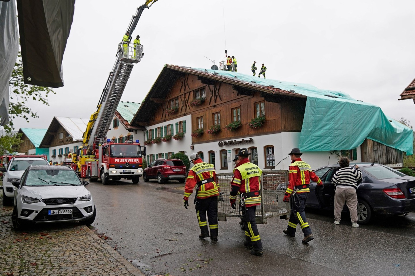 Arbeiter und Feuerwehrleute beseitigen die Unwetter-Schäden im oberbayerischen Bad Bayersoien. Bei dem Unwetter wurden viele Dächer beschädigt.