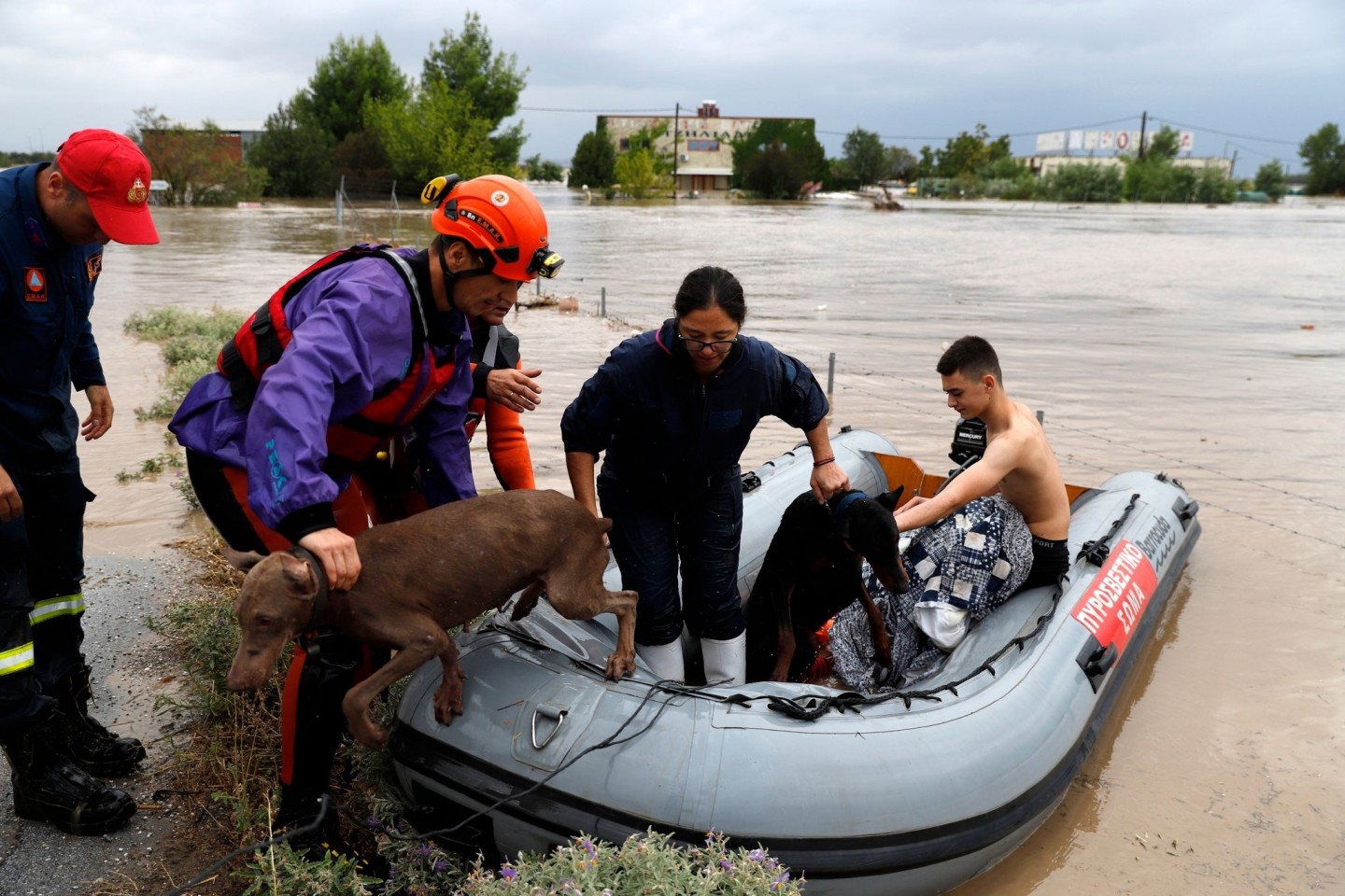 Feuerwehrleute mit einem Schlauchboot evakuieren Menschen und ihre Hunde aus überfluteten Gebäuden.