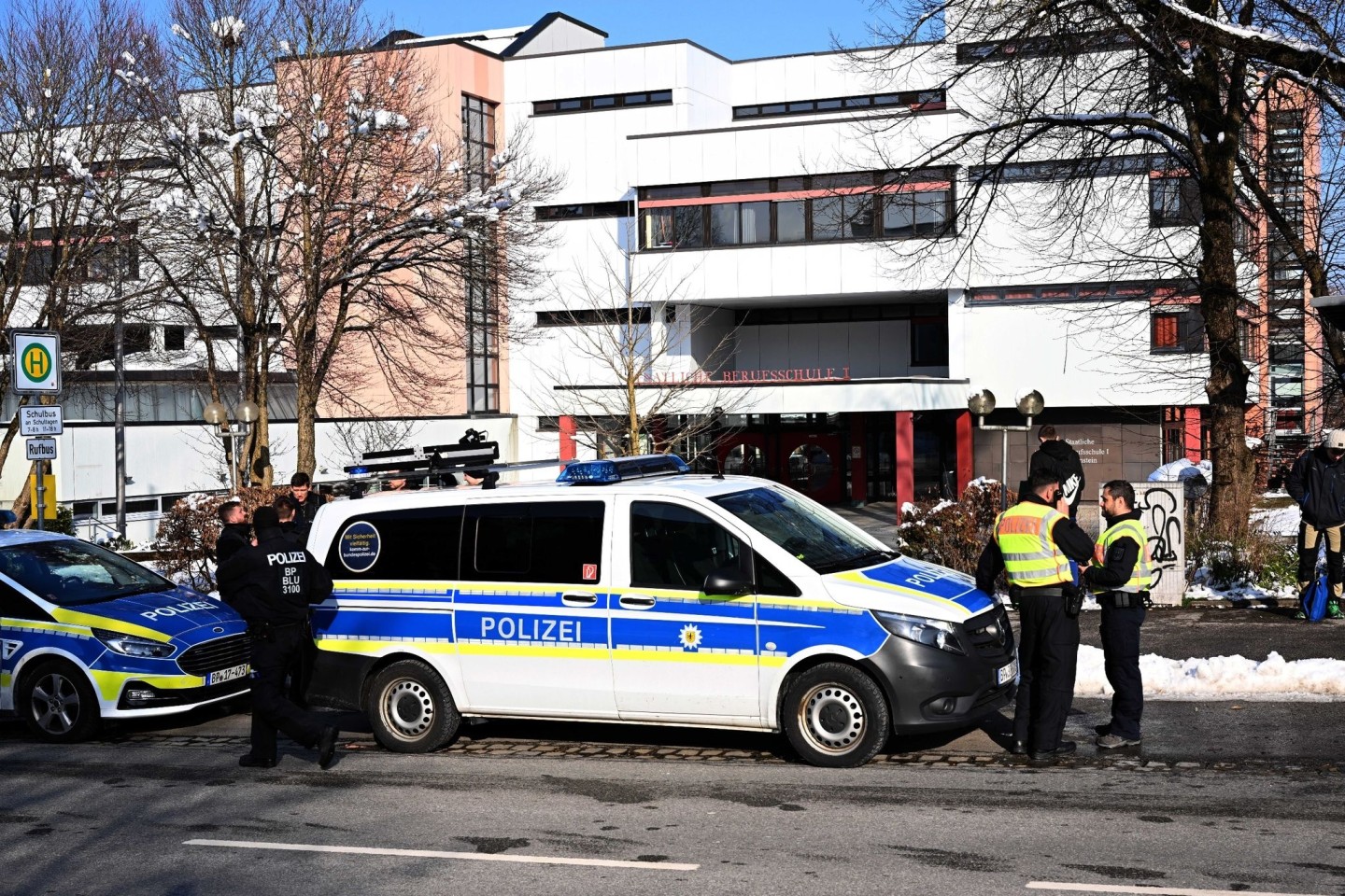 Polizeifahrzeuge und Polizisten stehen nach einem Großeinsatz an der Staatlichen Berufsschule I. in Traunstein.