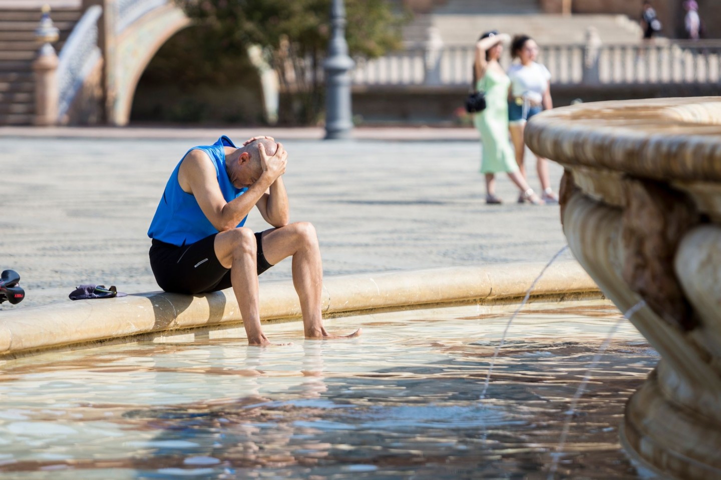 Ein Mann kühlt sich im zentralen Brunnen auf der Plaza de España in Sevilla ab.