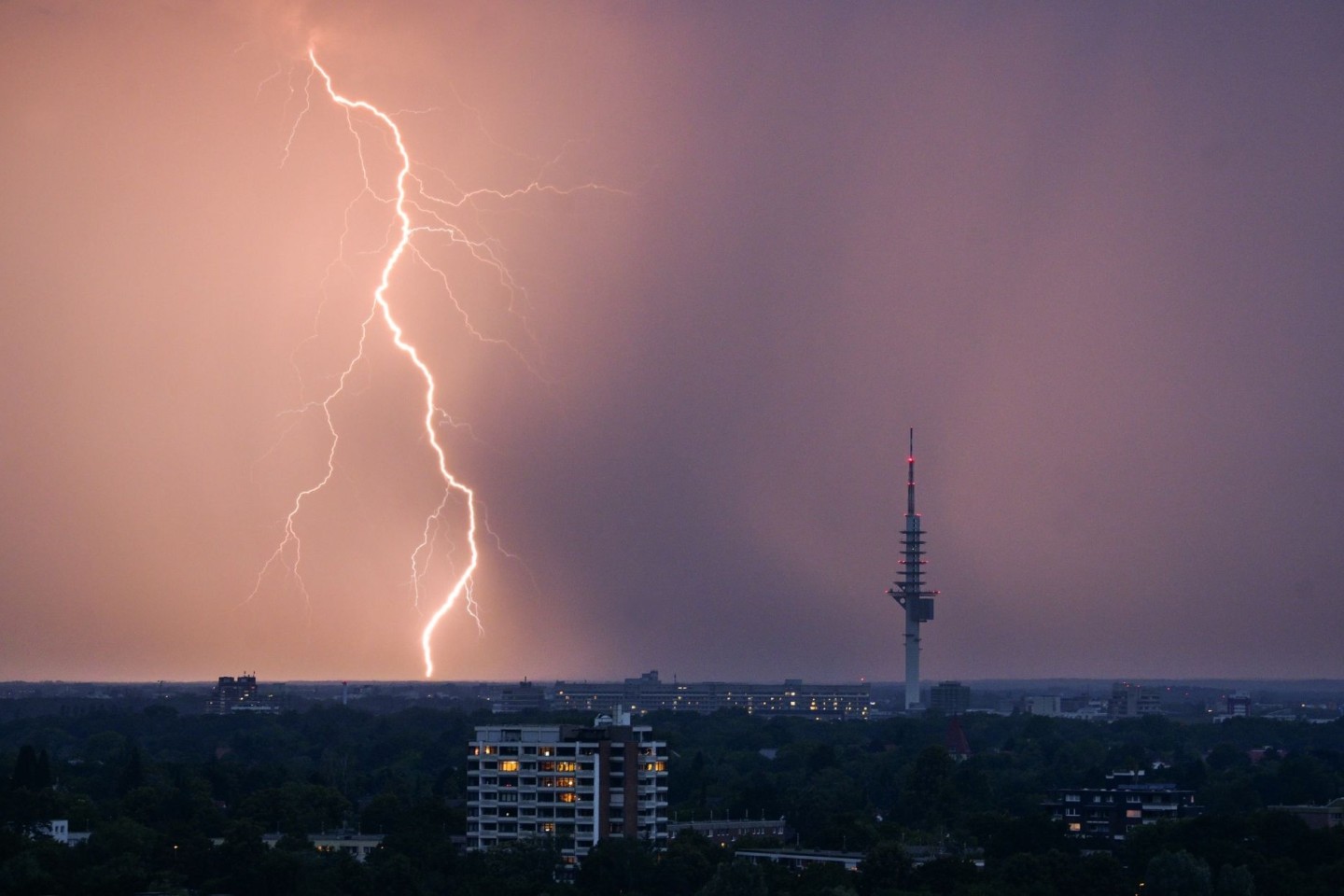 Ein Blitz entlädt sich während eines Gewitters hinter dem Fernmeldeturm Telemax.