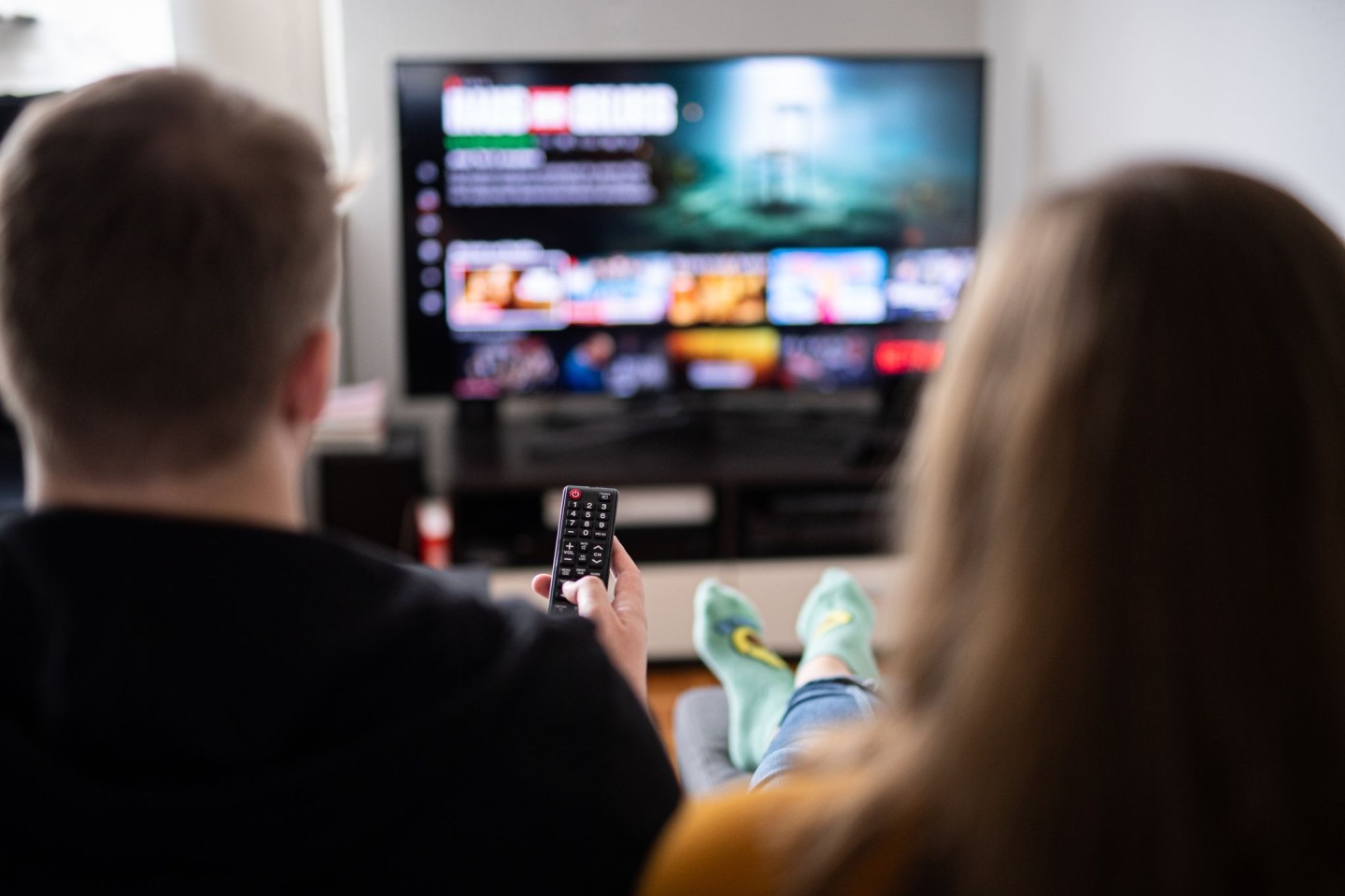 Ein junges Paar sitzt mit einer Fernbedienung vor einem Fernsehgerät. Das Fernsehen bleibt für Nachrichten für die meisten die wichtigste Quelle (Symbolbild).