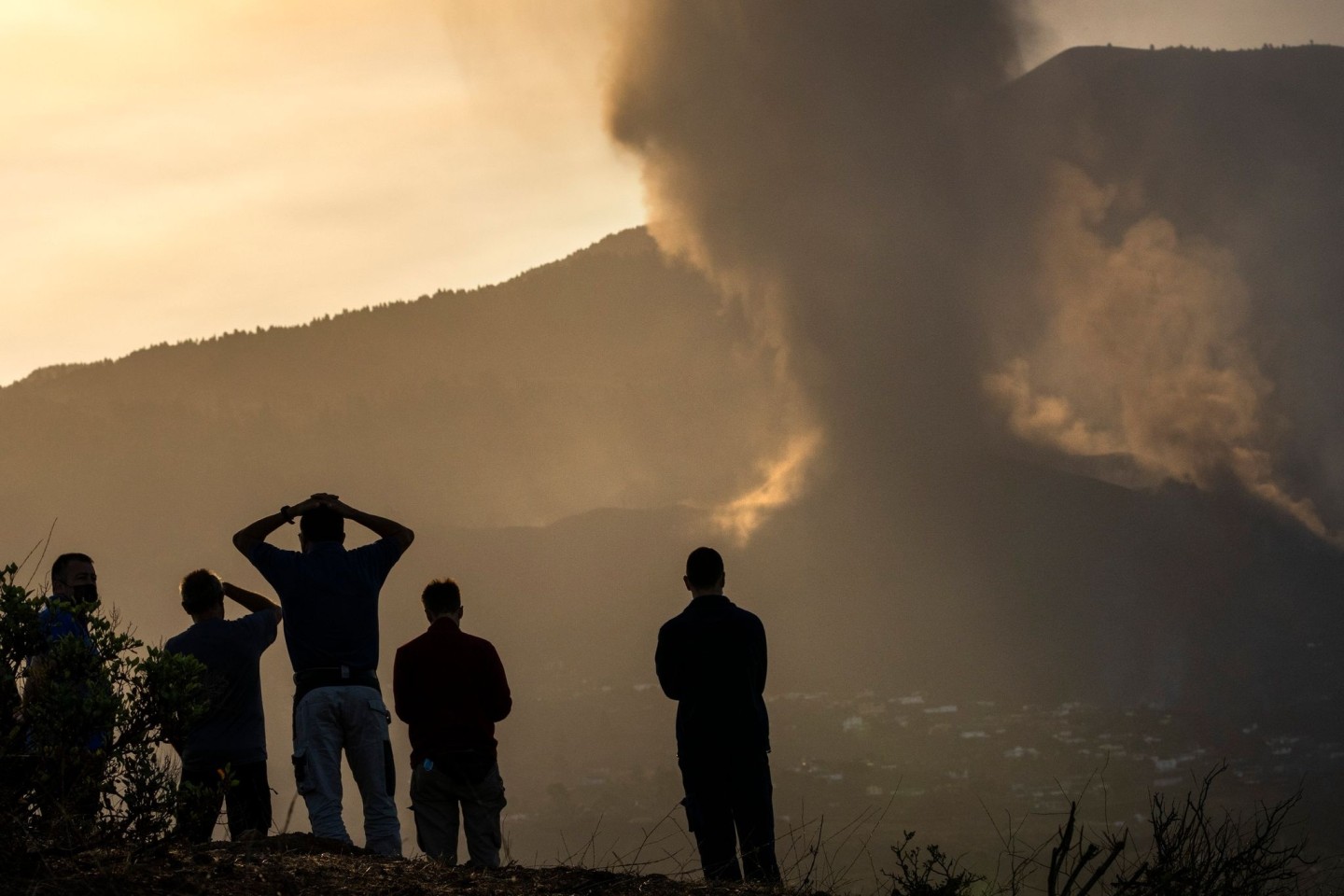 Anwohner blicken von einem Hügel aus auf die Lava, die weiterhin aus dem Vulkan auf der Insel La Palma fließt.