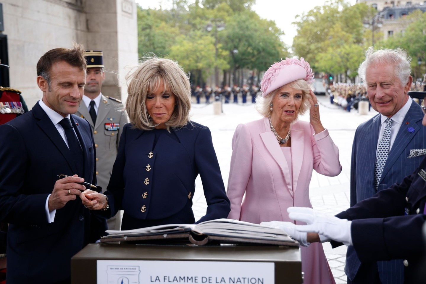 Präsident Emmanuel Macron (l-r) und und seine Ehefrau Brigitte Macron sowie Königin Camilla und König Charles III. von Großbritannien tragen sich während einer Zeremonie am Triumphboge...