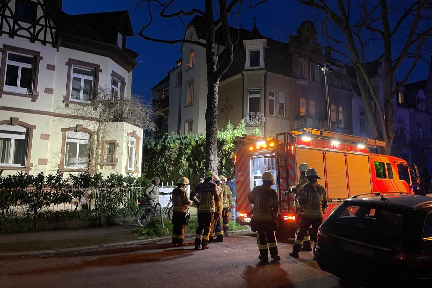 Einsatzkräfte der Feuerwehr stehen an dem Wohnhaus, in dessen Untergeschoss sich eine Explosion ereignete.