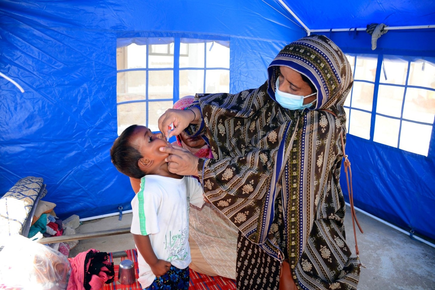 Nach den schweren Überschwemmungen in Pakistan verabreicht eine Mitarbeiterin des Gesundheitswesen einem Kind eine Schluckimpfung gegen Polio.