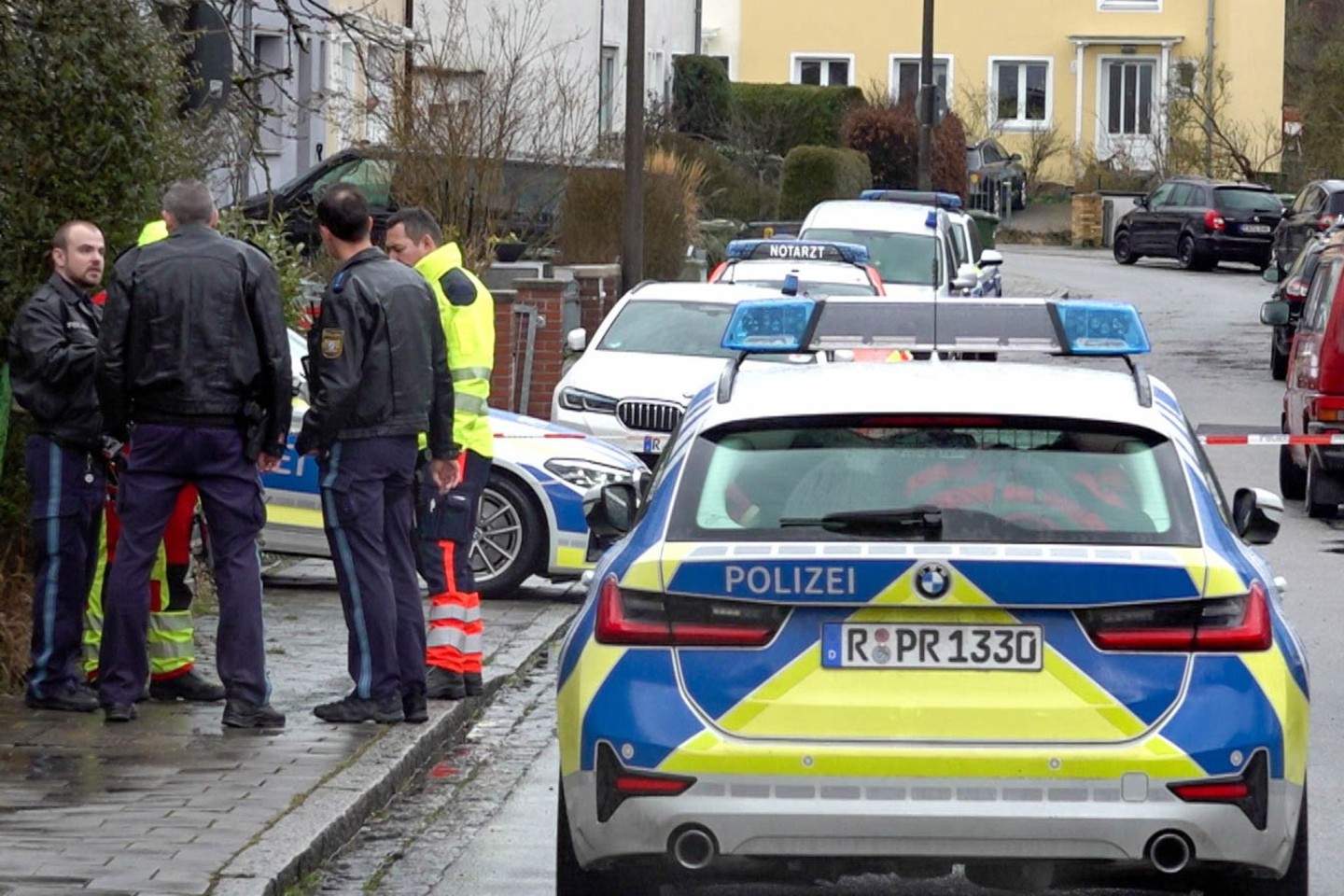 Polizei und Notarzt stehen vor dem Haus in Regensburg, in dem sich die Gewalttaten ereigneten.