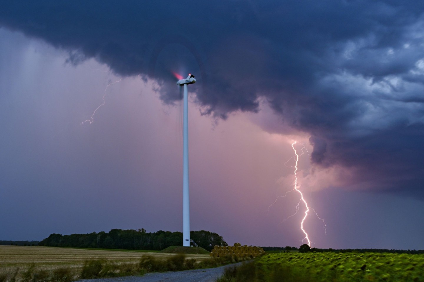 Ein Blitz leuchtet am Abendhimmel hinter einer Windenergieanlage im Osten Brandenburgs.