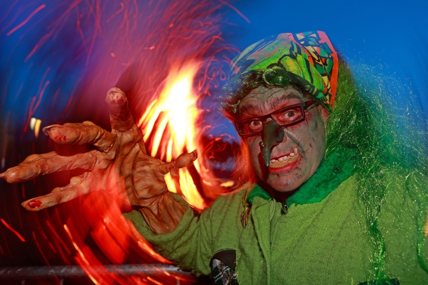 Im Hexenkostüm steht ein Besucher des Walpurgisfestes in Schierke am Feuer.