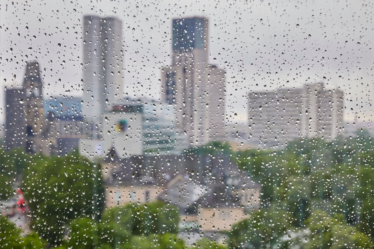 Regentropfen an einer Fensterscheibe vor der Skyline der City West in Berlin. Bleibt der Regen?