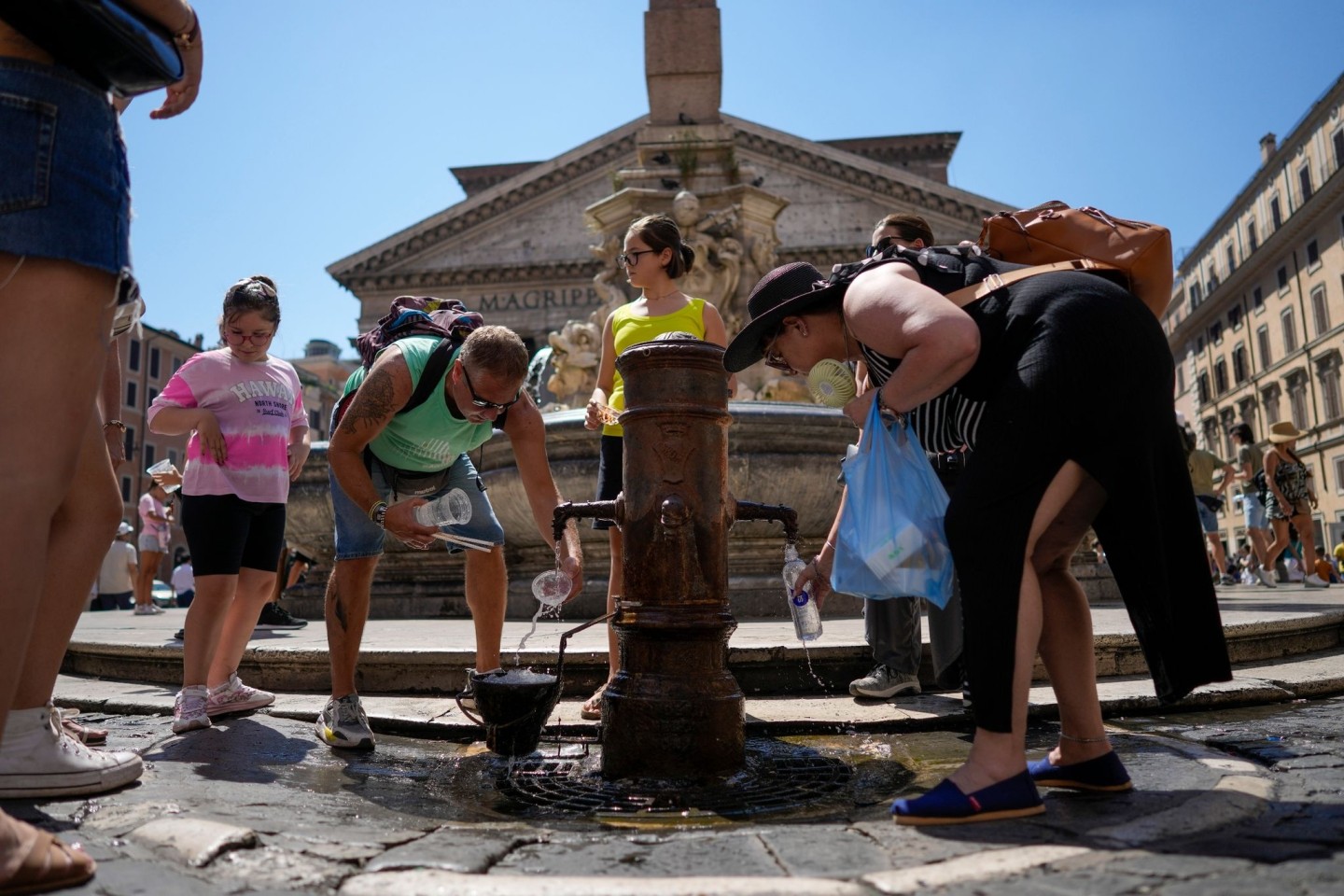 Menschen kühlen sich an einem Springbrunnen vor dem Pantheon in Rom ab.