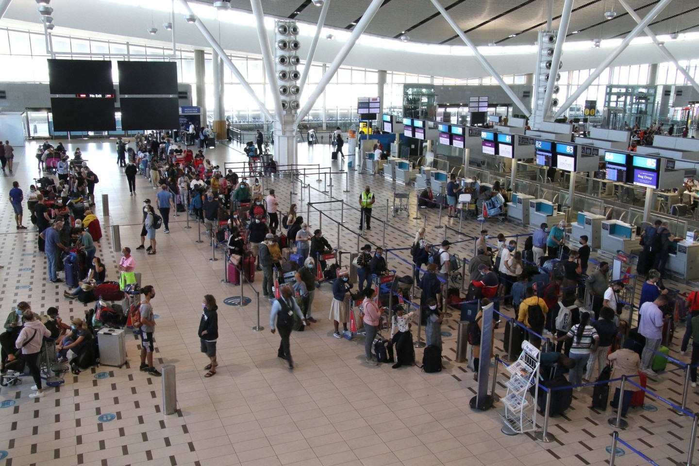Reisende stehen am Flughafen in Kapstadt in langen Schlangen an den wenigen Schaltern an, die überhaupt noch offen sind.