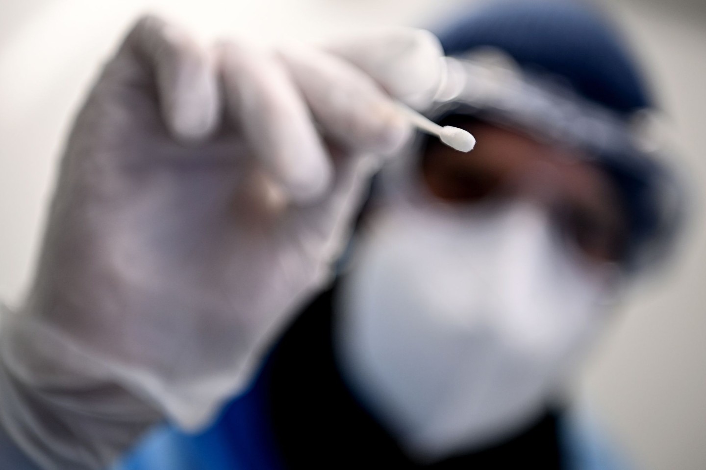 Ein Arzt beim Gesundheitsamt Neukölln hält ein Teststäbchen für einen PCR-Test in der Hand.
