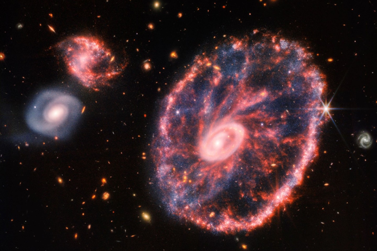 Dieses von der NASA zur Verfügung gestellte Handout-Foto zeigt eine große, rosa-blau gesprenkelte Galaxie, die einem Rad mit einem kleinen, inneren Oval ähnelt.
