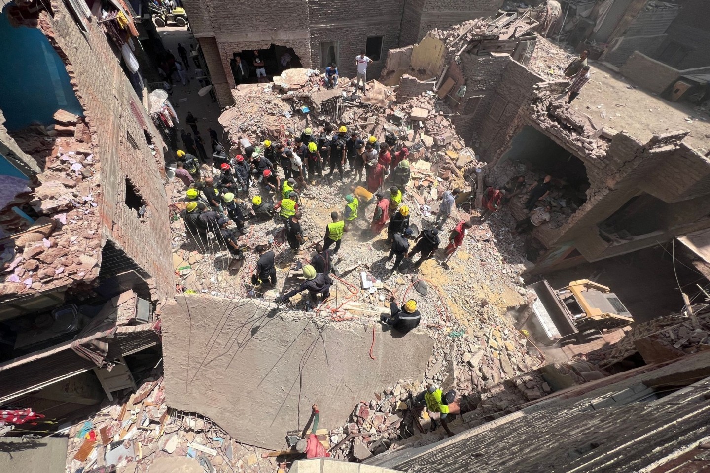 Rettungskräfte suchen nach Überlebenden in den Trümmern eines vierstöckigen Gebäudes, das im Stadtteil Hadayek al-Kobba eingestürzt ist.