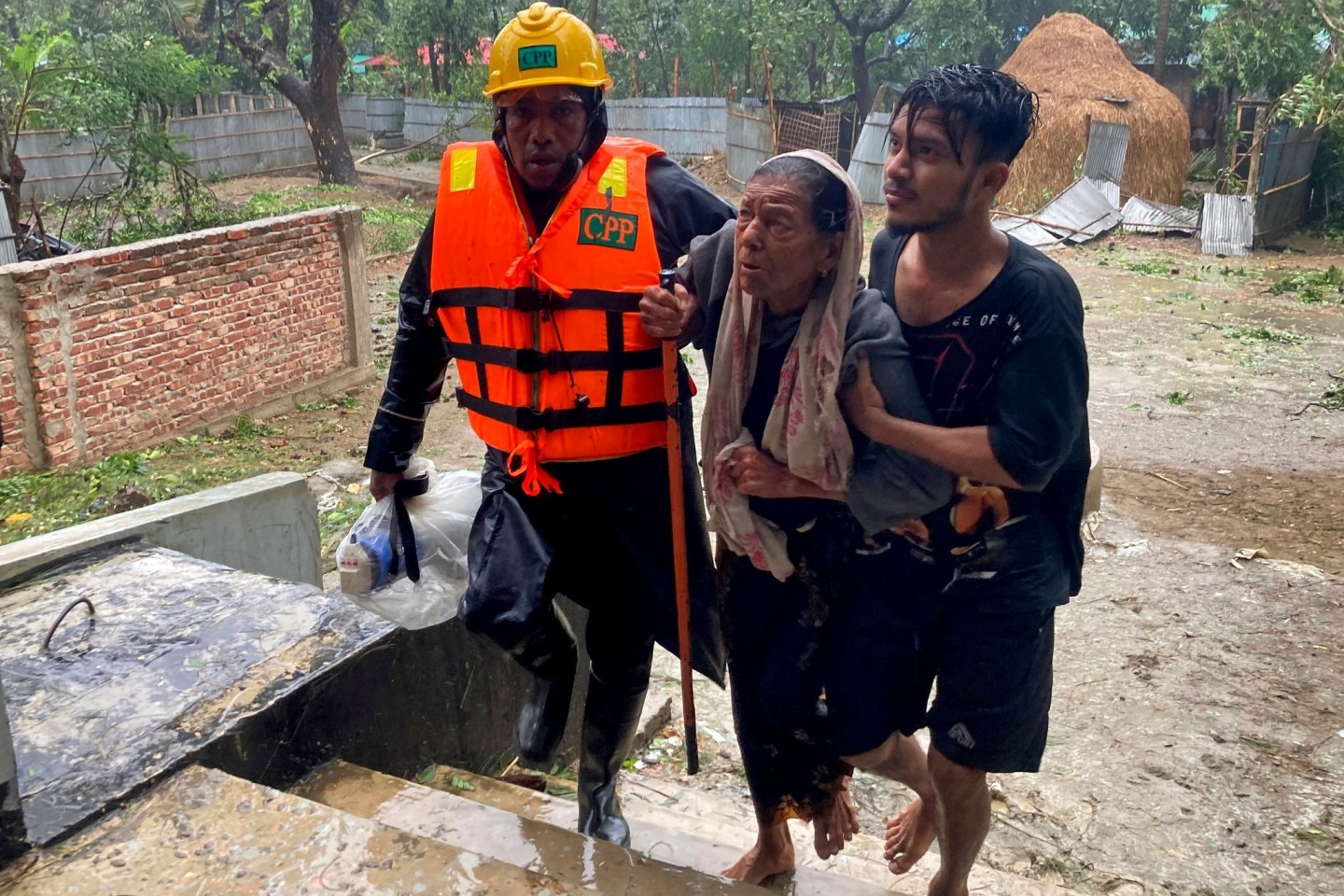 Rettungskräfte helfen einer älteren Frau, eine Notunterkunft in Cox's Bazar zu erreichen.