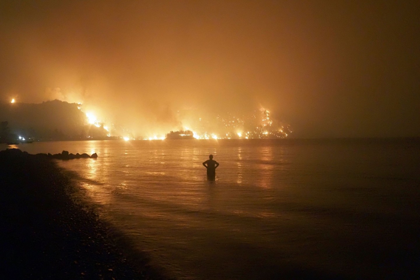 Ein Mann beobachtet im August 2021, wie sich Waldbrände dem Strand von Kochyli in der Nähe des Dorfes Limni auf der Insel Evia (Griechenland) nähern.