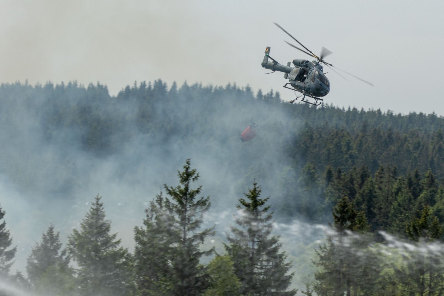 Die Feuerwehr versucht mit einem Hubschrauber einen Moorbrand im deutsch-belgischen Grenzgebiet bei Aachen zu löschen.