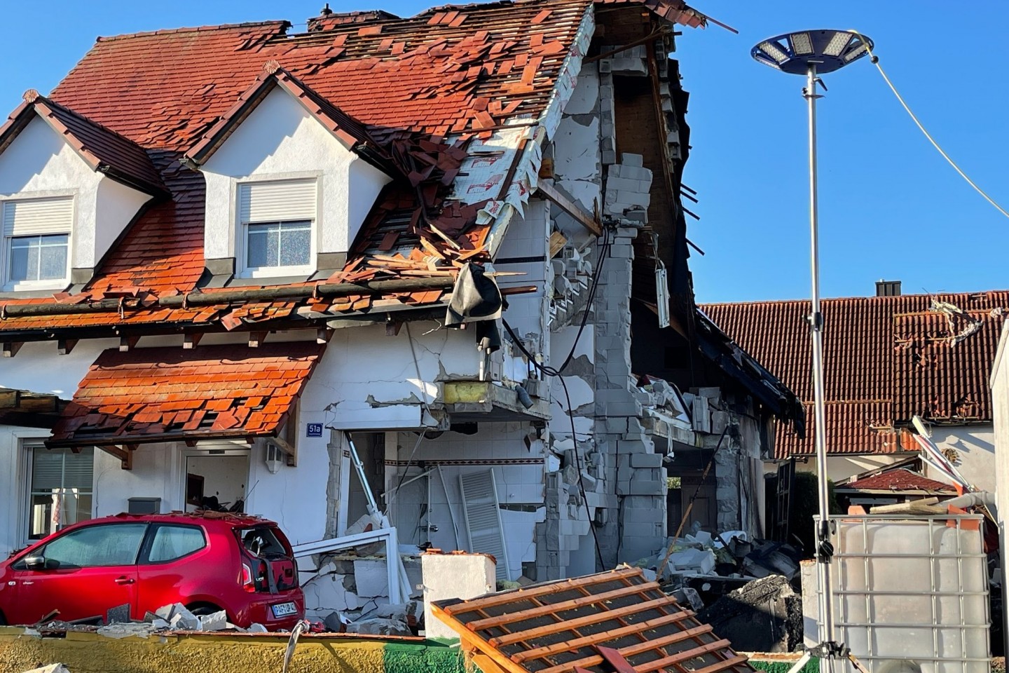 Nach der Explosion eines Wohnhauses ist das Nachbarhaus von Beschädigungen schwer gezeichnet.