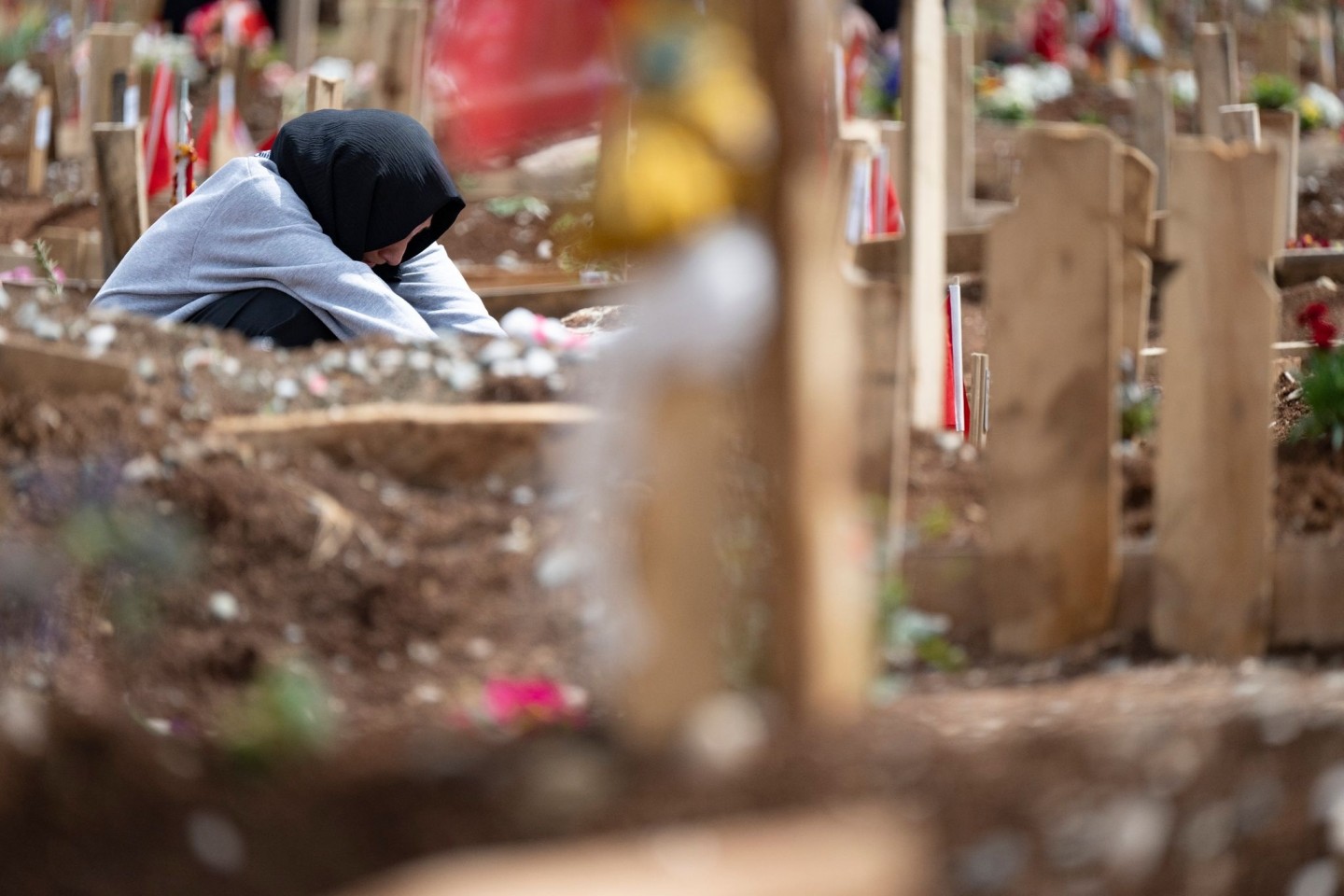 Weinend sitzt eine junge Frau am Grab ihrer Schwestern, die bei dem Erdbeben im Februar ums Leben gekommen waren.