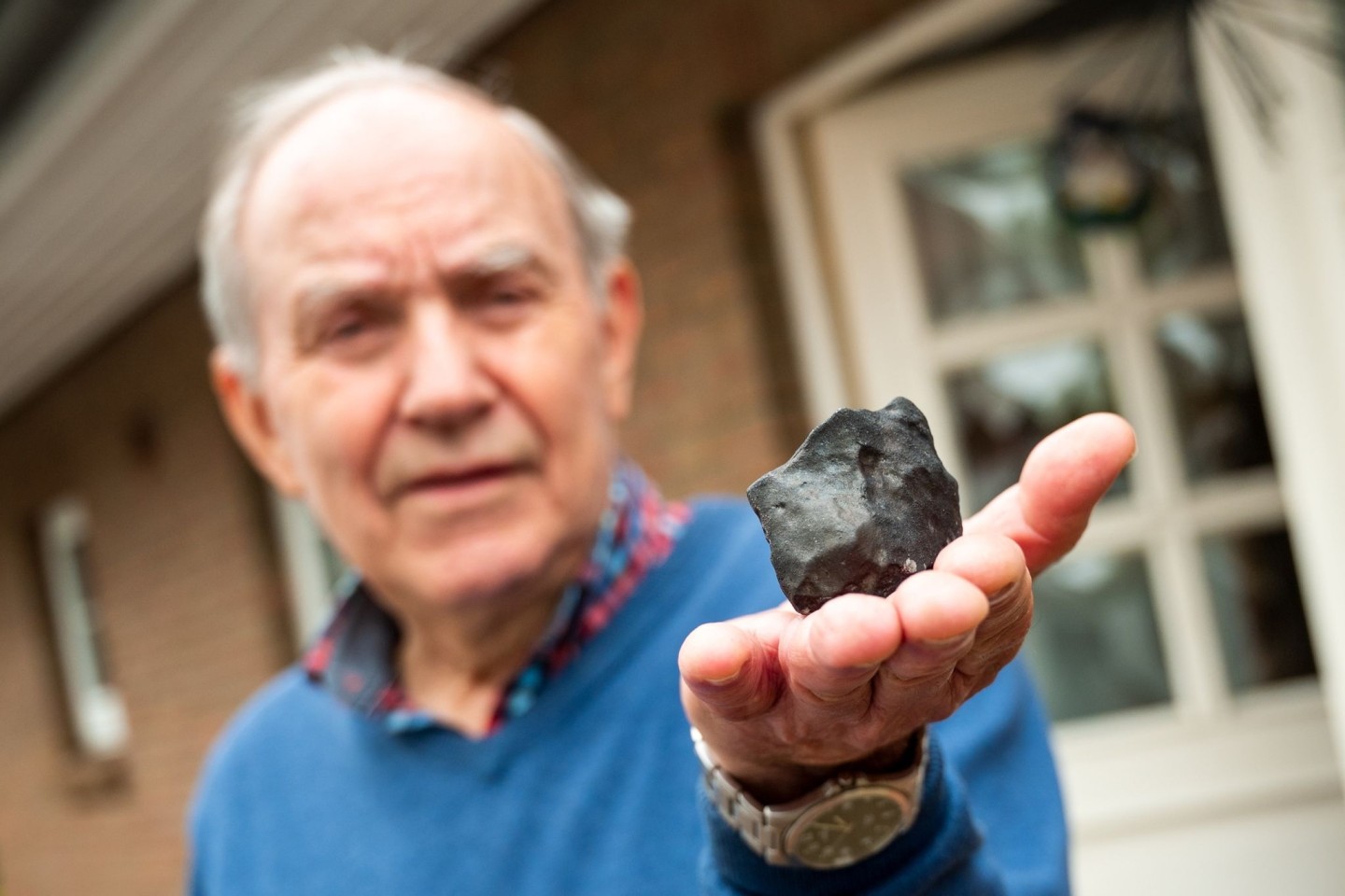 Wilfried Labusch hält einen kleinen Meteoriten, der in sein Haus niedergegangen ist.