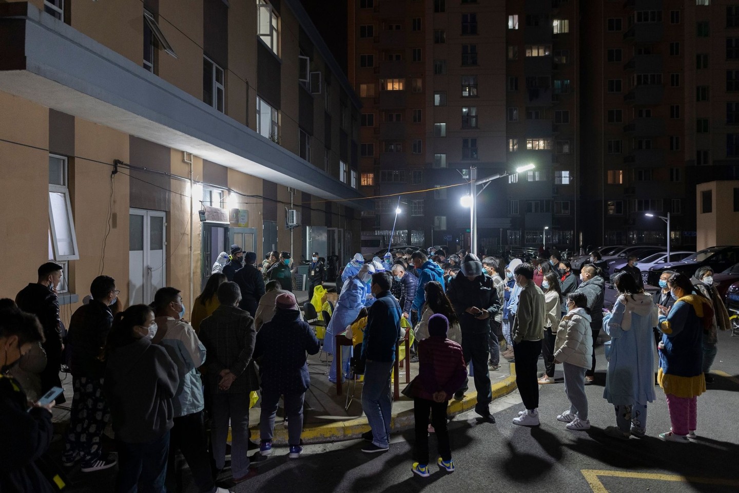 Anwohner einer Wohnsiedlung stehen in Shanghai für einen Corona-Massentest Schlange.