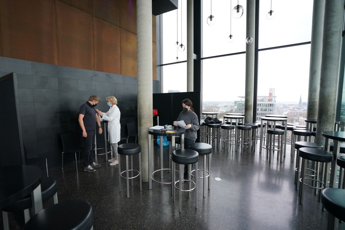 Ein Mann lässt sich in der Skyline Bar 20up im 20. Stock des Empire Riverside Hotels am Hamburger Hafen impfen.