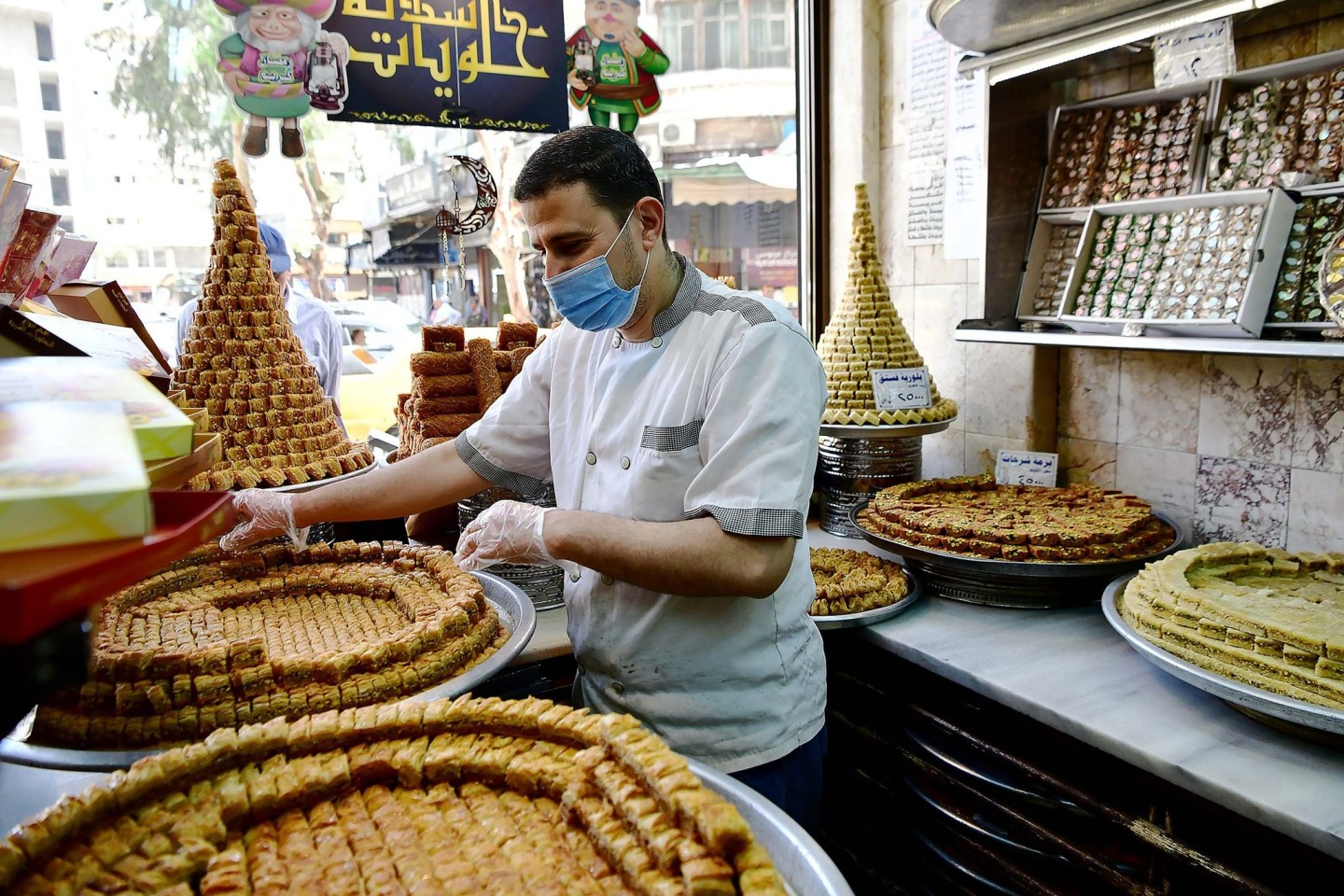 Ein Konditor arrangiert Baklava in einem Geschäft in Syrien. Muslime auf der ganzen Welt feiern das Fest des Fastenbrechens Eid al-Fitr.
