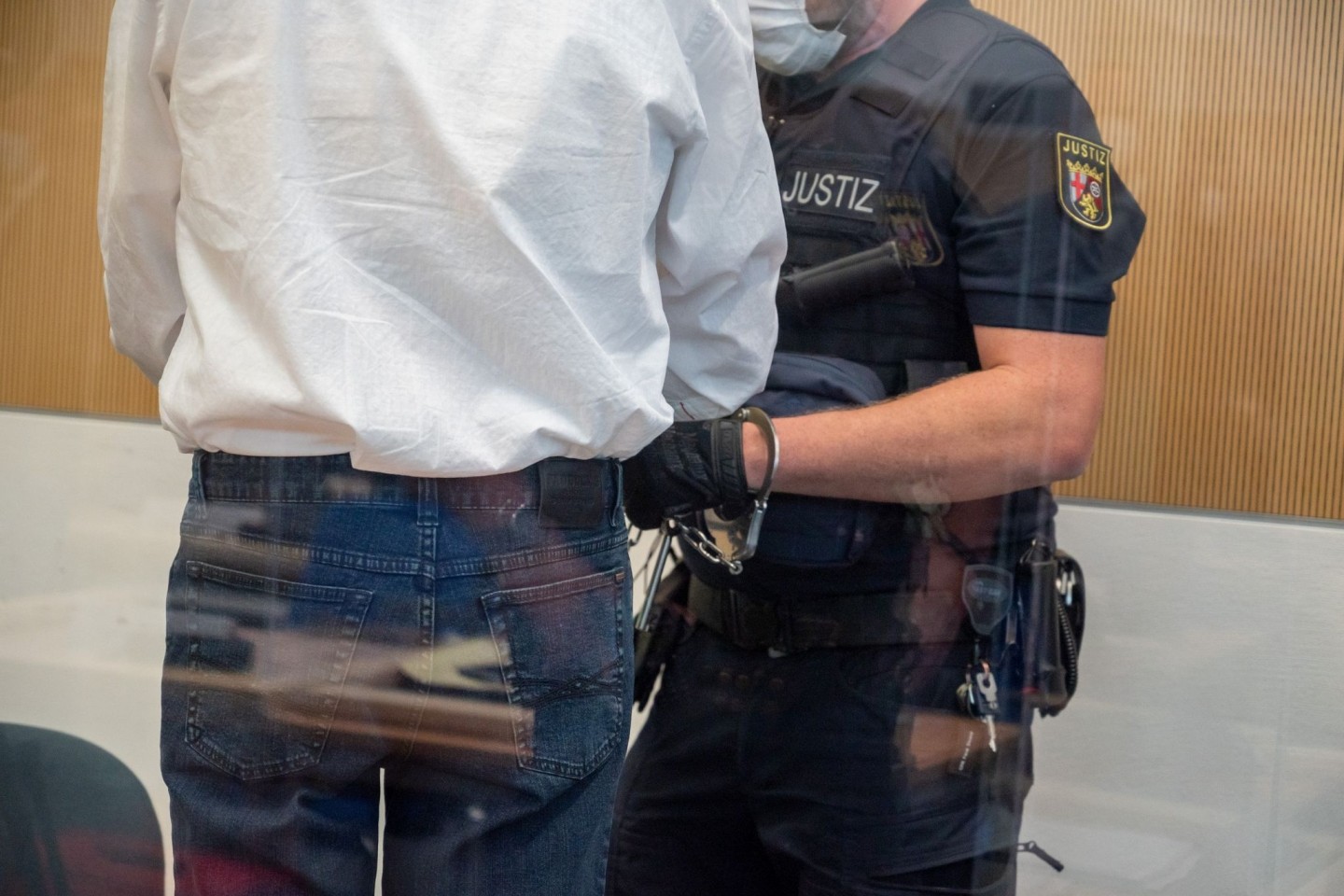 Ein Justizbediensteter überprüft im Landgericht Trier die Handfesseln des Angeklagten.