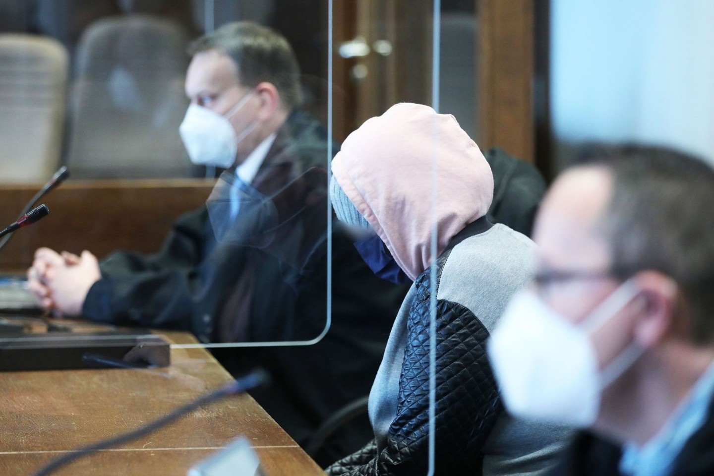 Die angeklagte Mutter (M) zwischen Anwälten im Gerichtssaal in Köln.