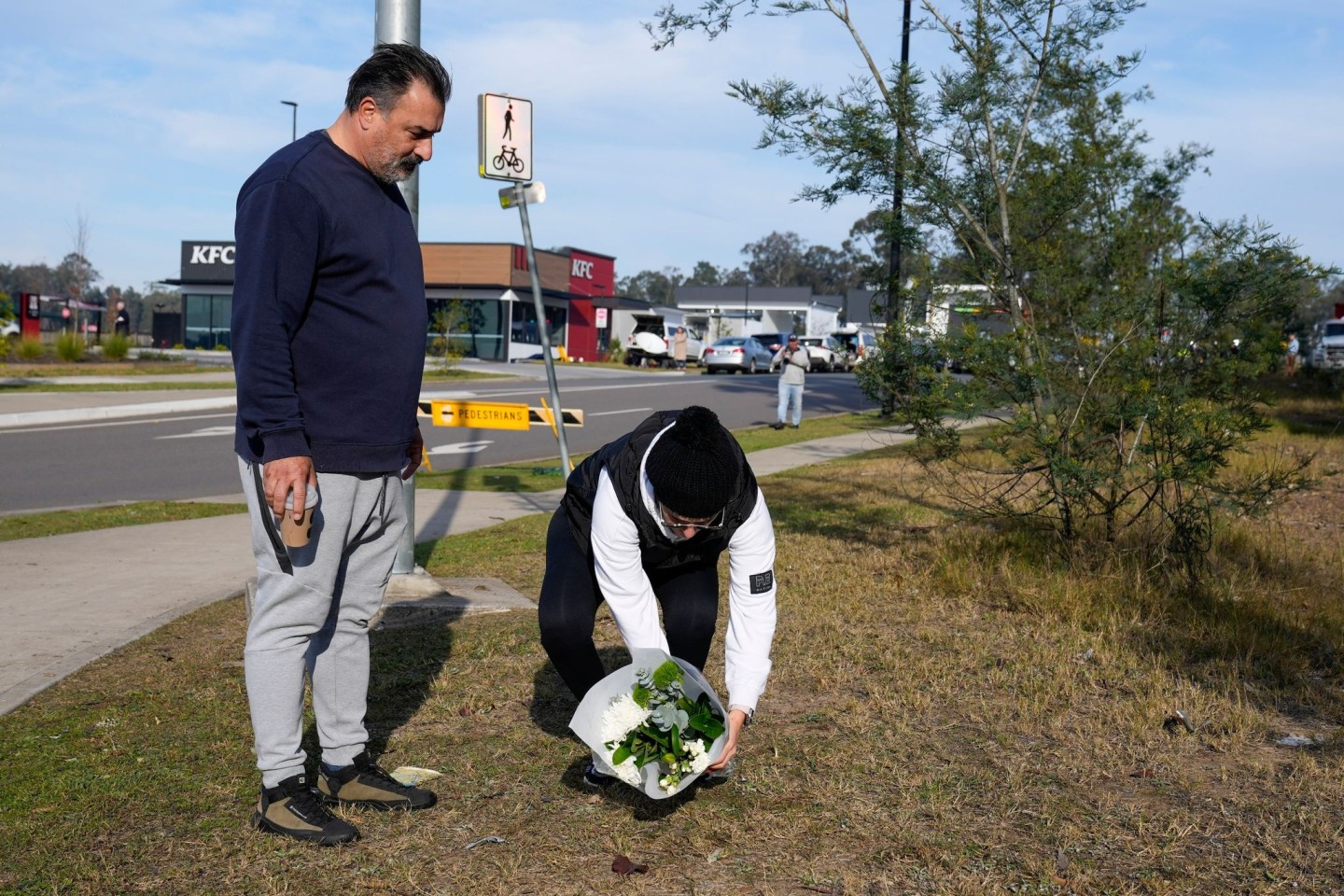 Ein Paar legt Blumen an einer Straßensperre in der Nähe des Unglücksortes nördlich von Sydney ab.