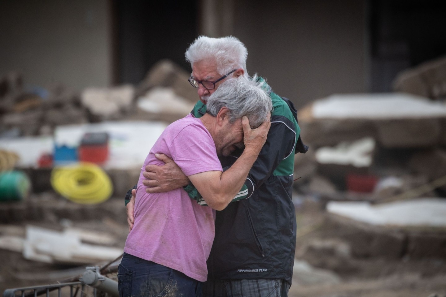 Weinend liegen sich die Brüder Bernd (l) und Gerd Gasper vor ihrem von der Flut zerstörten Elternhaus in Altenahr in den Armen.