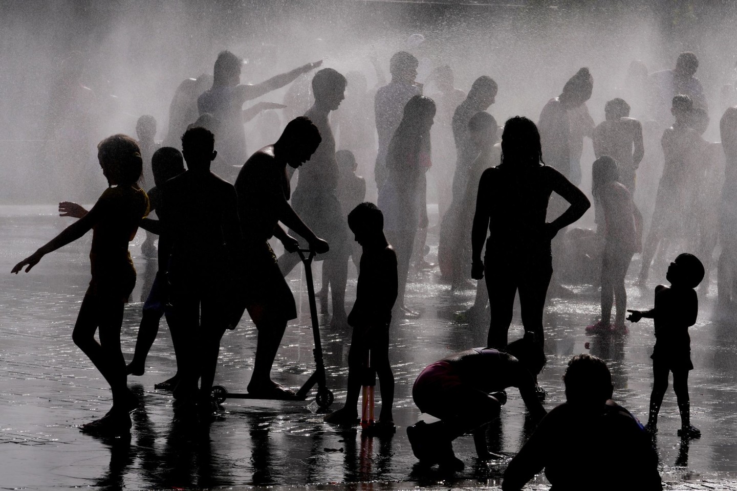 Kinder und Erwachsene erfrischen sich in einem Springbrunnen in einem Park in Madrid