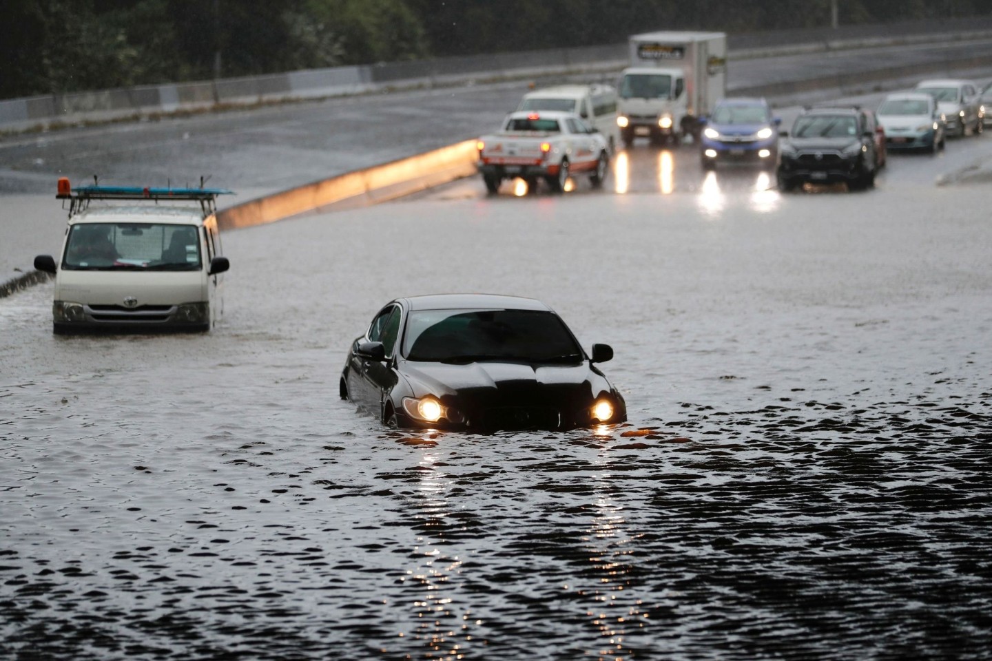 Fahrzeuge im Hochwasser auf einer überschwemmten Straße in Auckland.