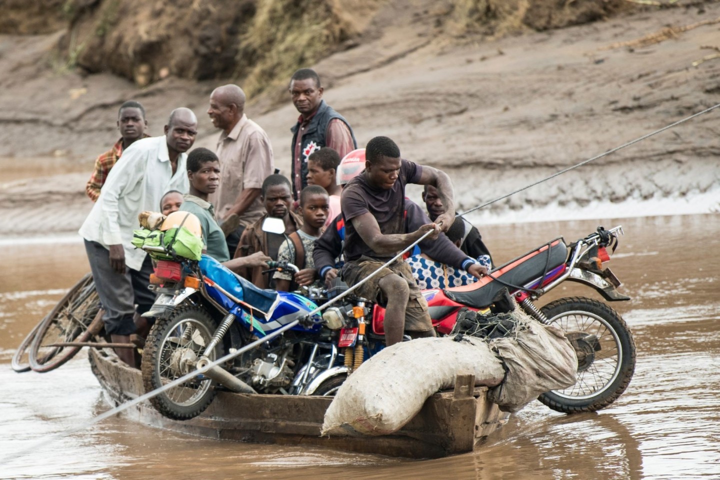 Männer transportieren in Malawi ihre geretteten Habseligkeiten mit einem Holzboot.