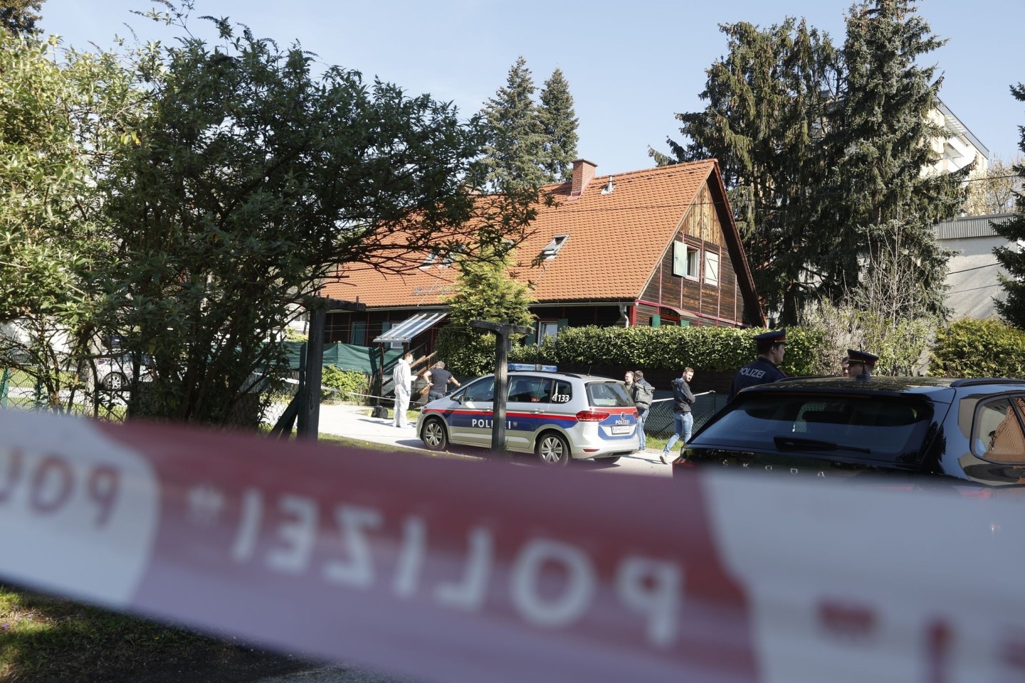 Polizisten in Graz stehen vor dem Wohnhaus, in dem eine 39-Jährige getötet wurde.