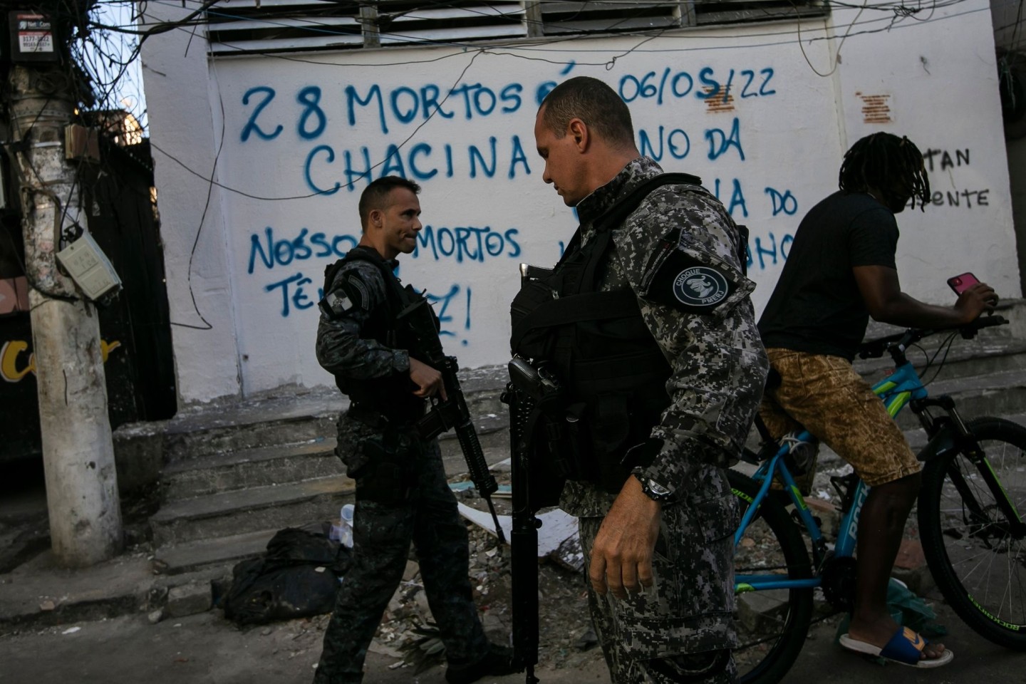 Bereitschaftspolizisten patrouillieren in Rio De Janeiro. Auf der Mauer hinter ihnen steht in portugiesischer Sprache: 