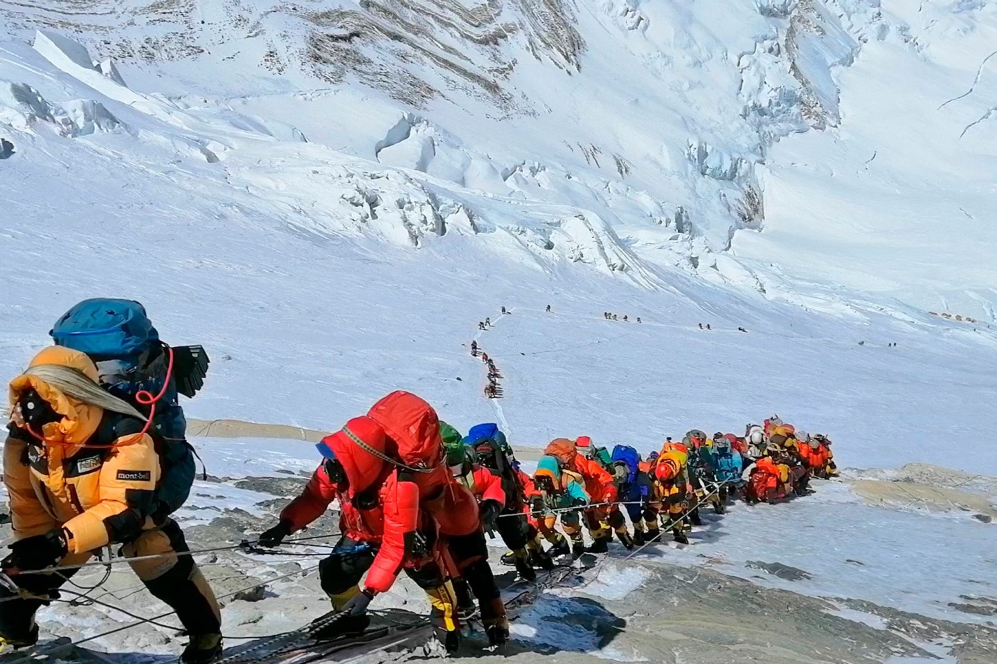 In einer langer Schlange klettern Bergsteiger auf einem Pfad am Mount Everest.
