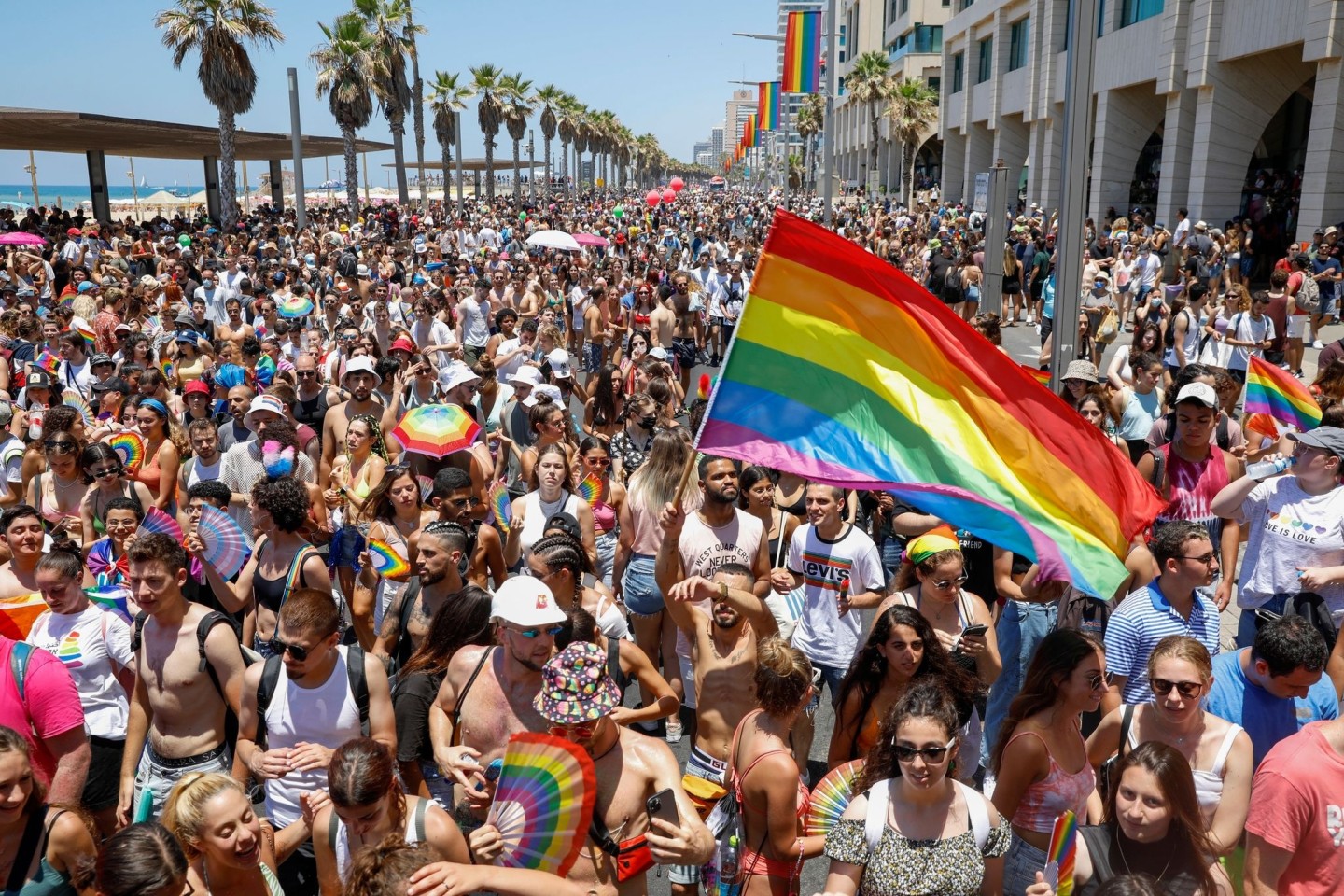 Teilnehmer schwenken Fahnen, Fächer und Schirme in Regenbogenfarben bei der Gay-Pride-Parade.