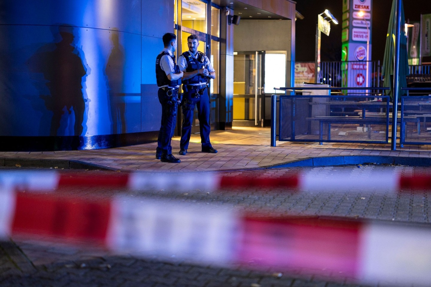 Zwei Polizisten vor einem Fast-Food-Restaurant in Oberhausen, in dessen Außenbereich Schüsse gefallen waren.