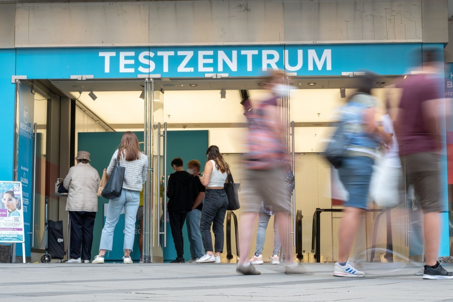 Passanten gehen an einem Corona-Testzentrum in der Münchner Innenstadt vorbei.